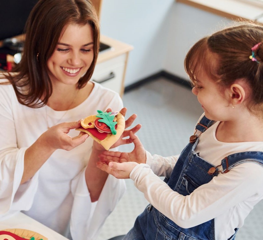 Teacher and child engaged in pretend kitchen play