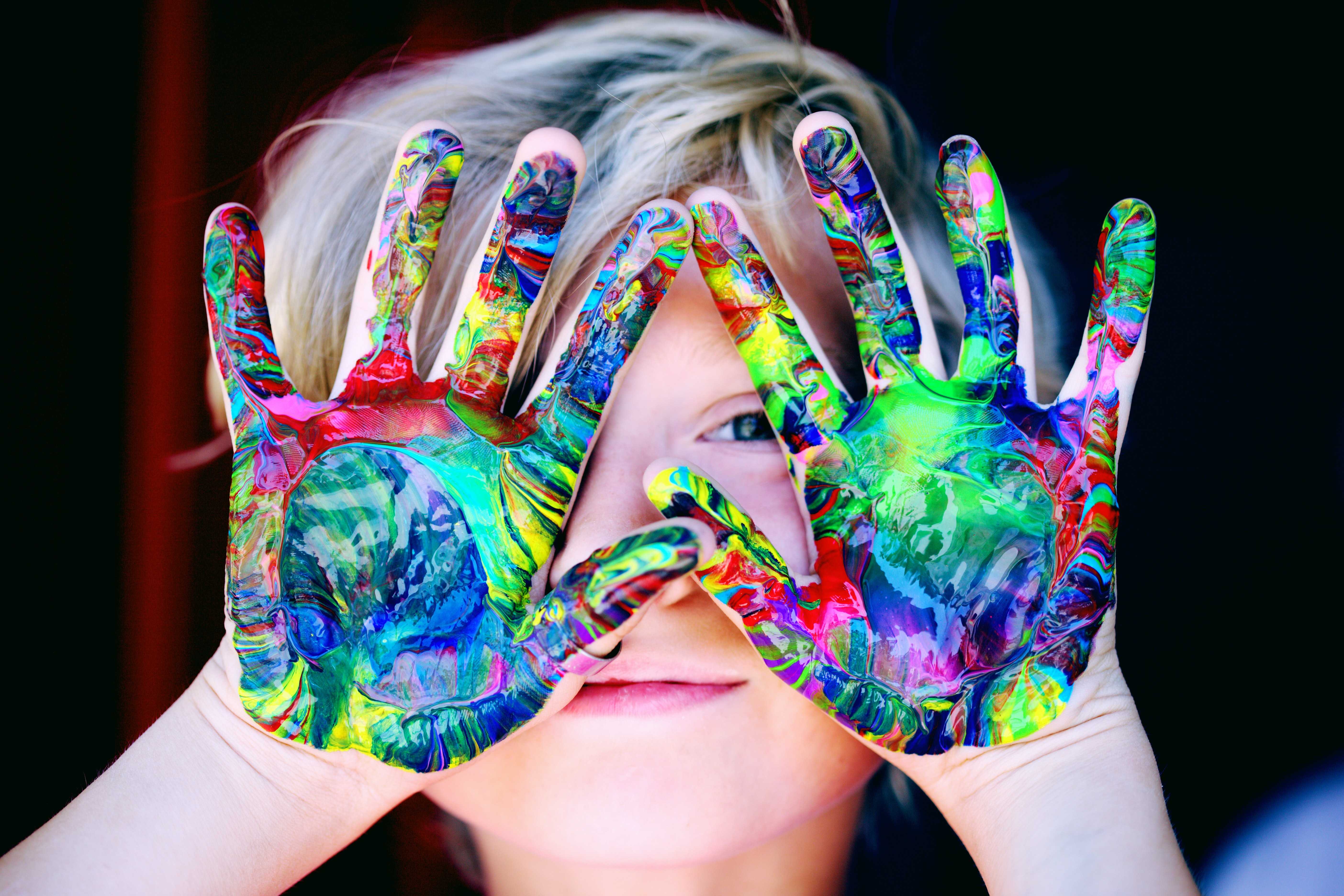 child with rainbow paint on hands